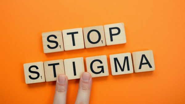 Wooden blocks spell 'Stop Stigma', fingers walking.