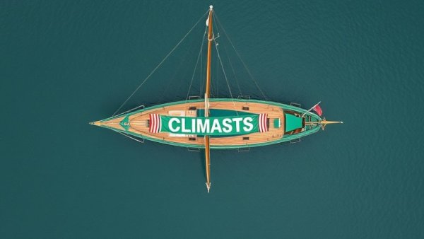 Green sailing ship with climate message banner at sea, linking COP30 and sailing.