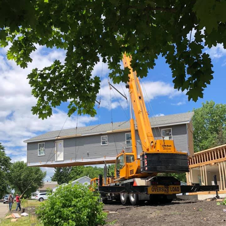 focused craneservices operator, concentrated expression, maneuvering control levers, photorealistic, enclosed cabin surrounded by a panoramic view, highly detailed, reflective windows, precise depth of field, uniform green and grey, diffuse lighting, shot with a 35mm lens.