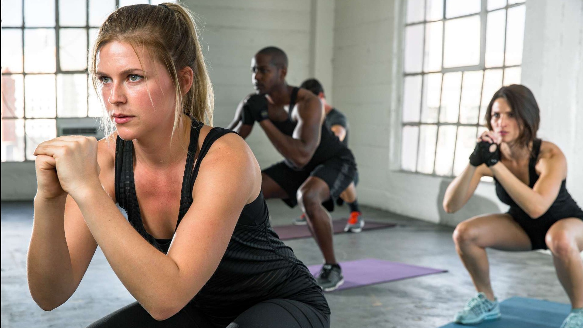 Energetic fitness coach motivating a diverse group mid-HIIT workout, showcasing determination.