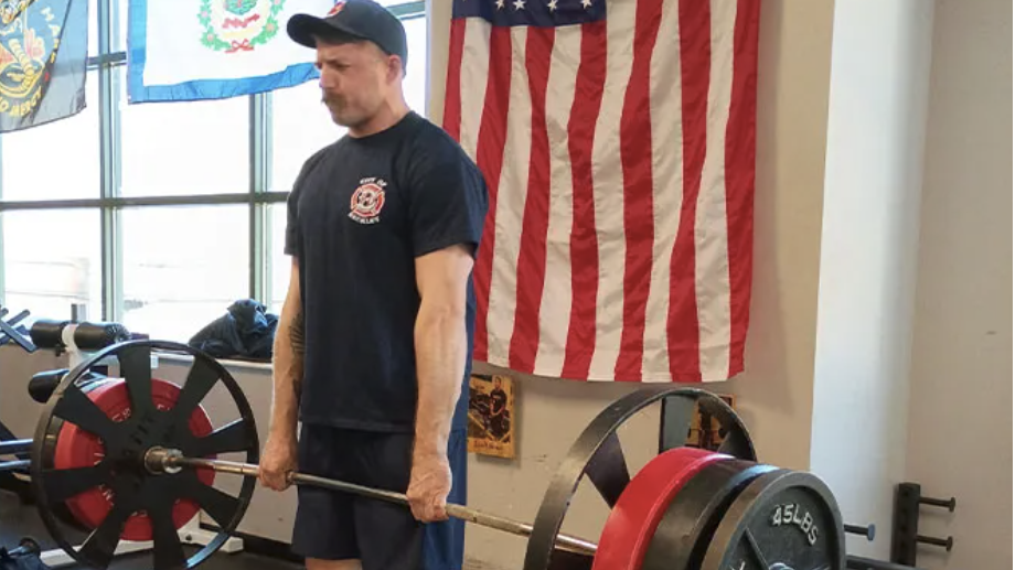 Strongman contest: competitor pulling fire truck in park.