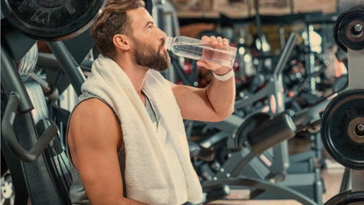 Energetic young athlete wiping sweat, holding a water bottle, bright daylight.