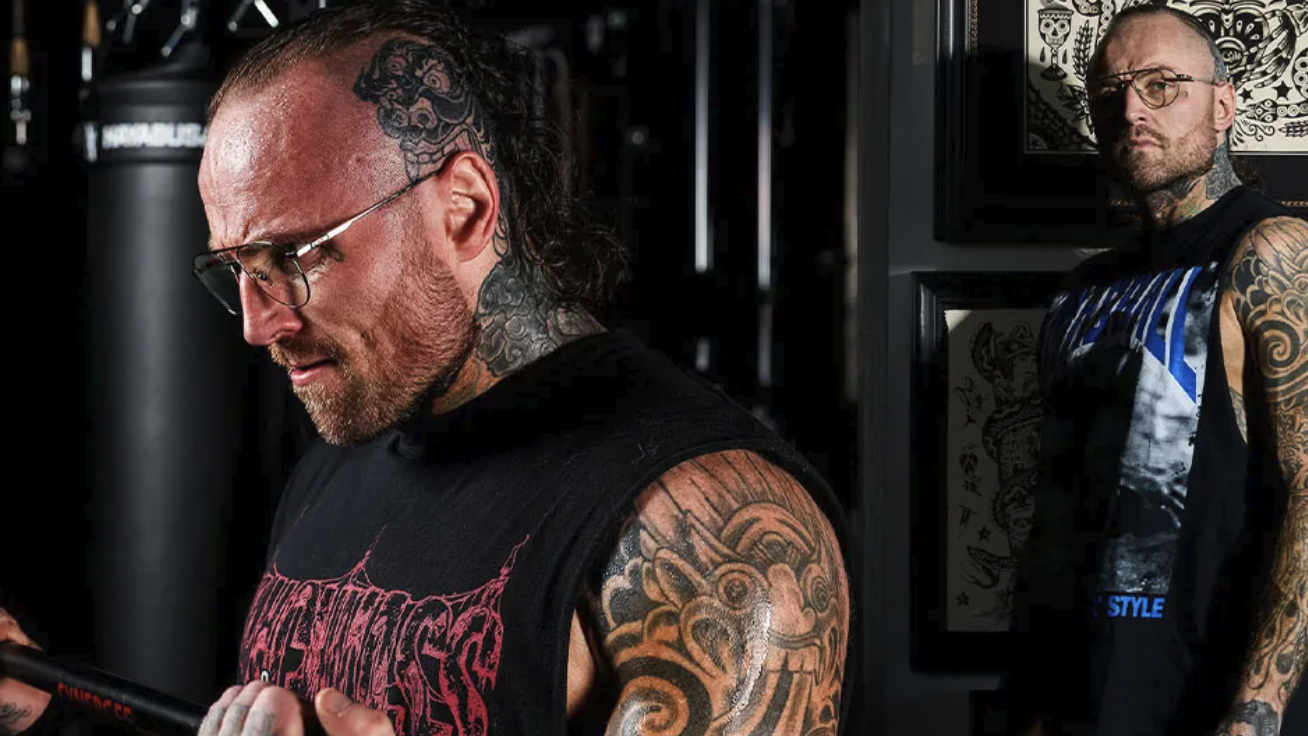 Tattooed muscular male working out intensely in gym.