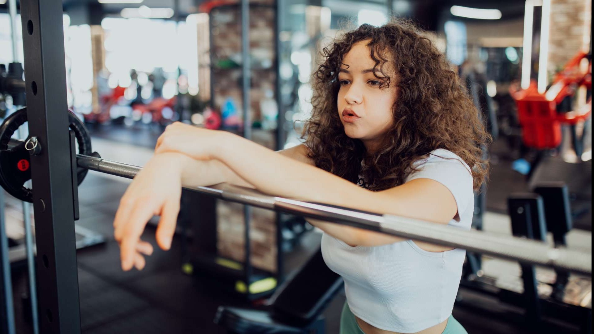 Beginner strength workout: young person focused on barbell lift in soft morning light.