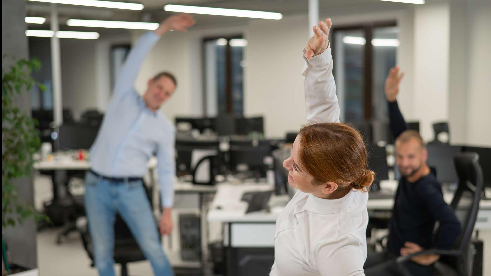 Determined young professional doing desk exercises for health in a bright, minimalist setup.