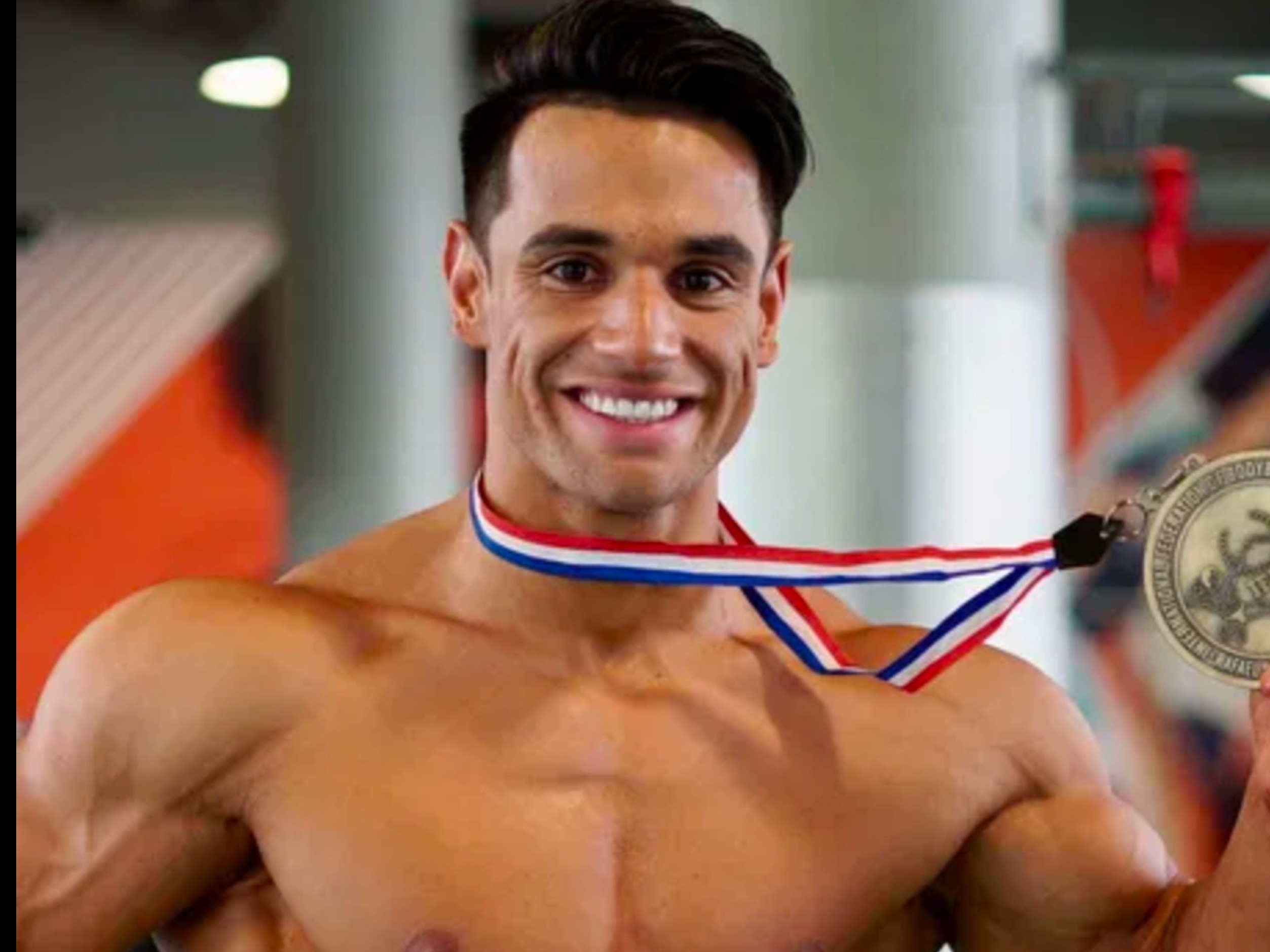 Bodybuilder at Arnold expo posing on stage with a confident smile.