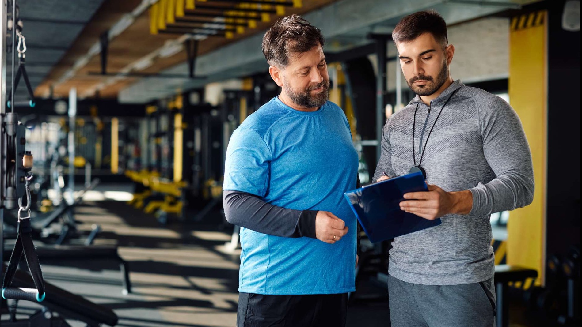 Muscular young man in gym with dumbbells, focused on muscle growth.