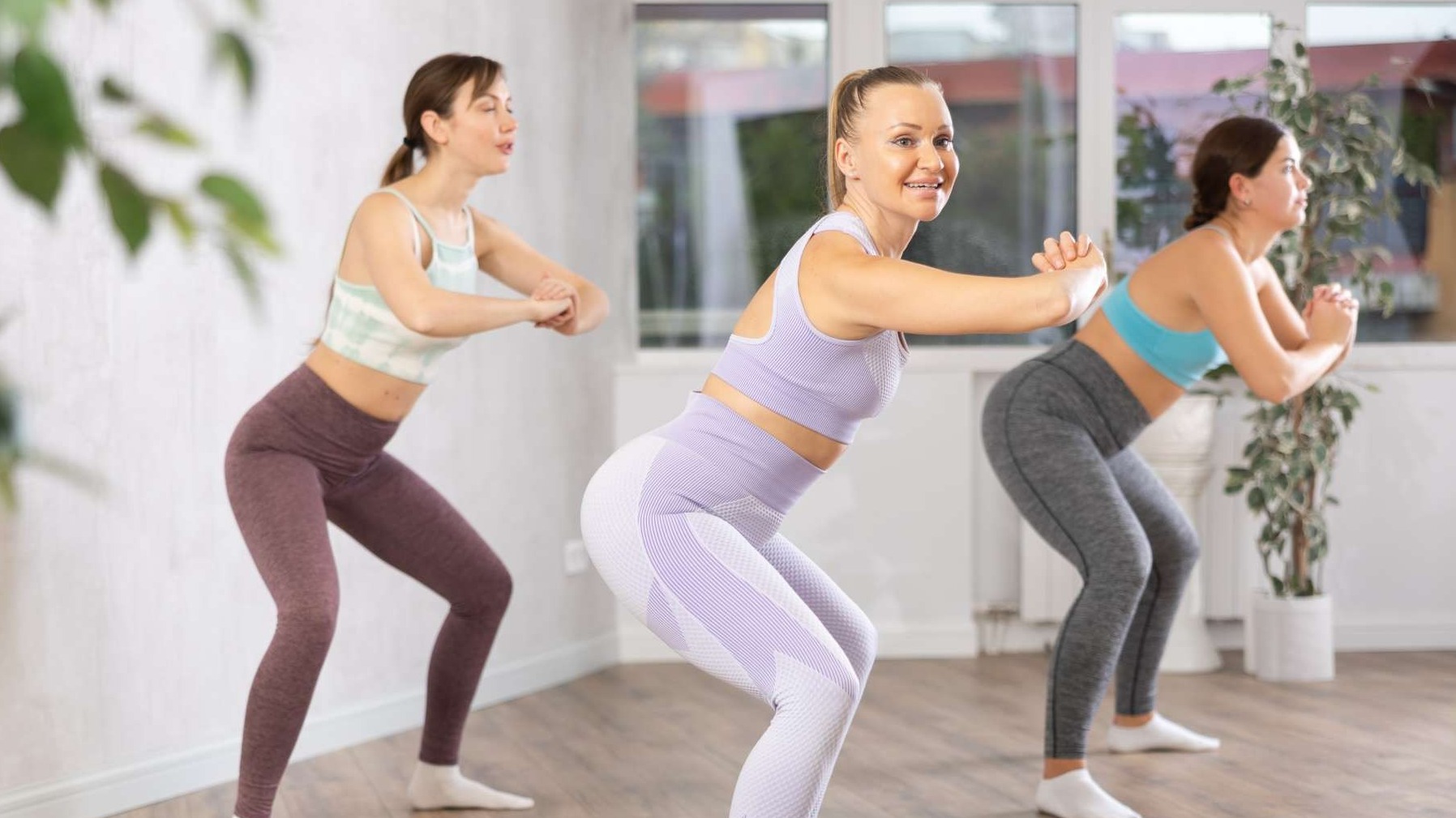 Confident woman lifting barbell for muscle growth in a gym setting.
