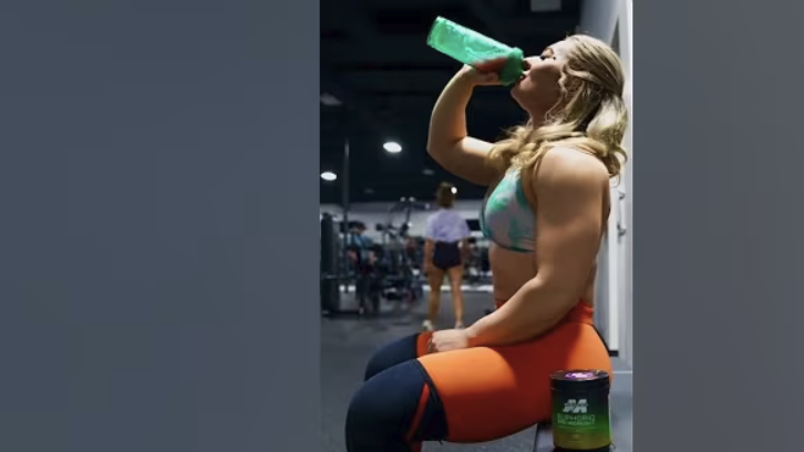Woman performing bodyweight glute workout in gym.