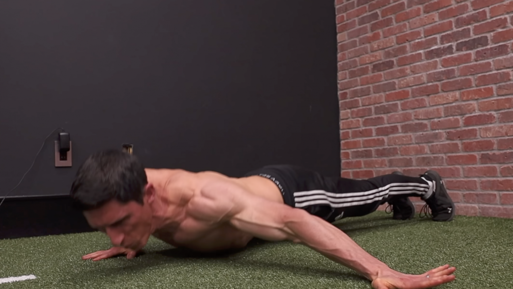 Muscular man showcasing effective bodyweight exercises outside a gym.