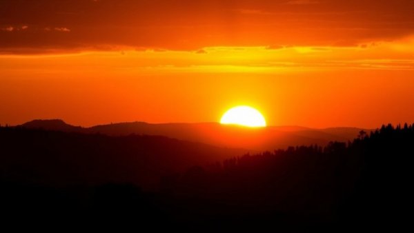 Intense sunset over silhouetted mountains related to heatstroke symptoms.