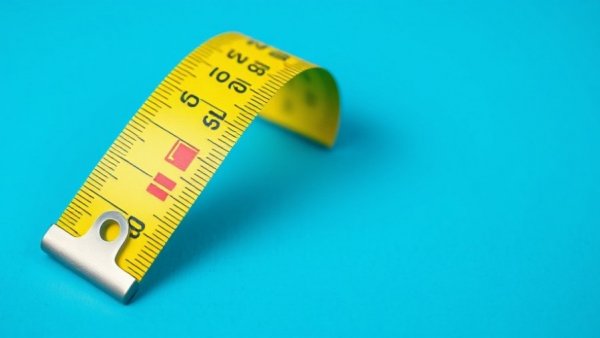 Yellow tape measure with red squares on blue background.