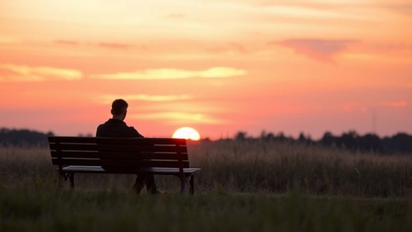 Person sitting alone on bench during sunset, effects of loneliness on mental health.