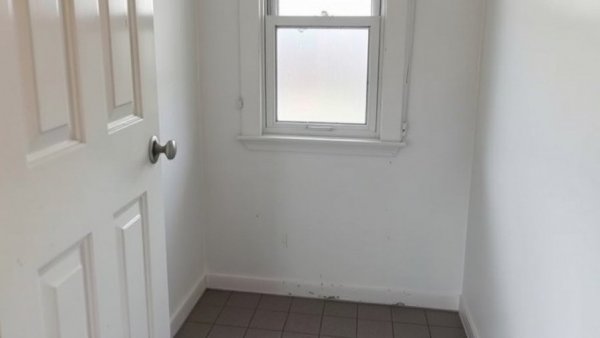 Outdated bathroom corner with peeling door and frosted window.