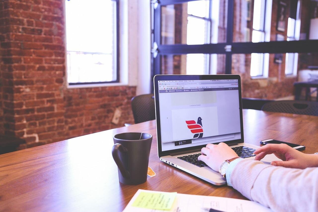 hands typing on laptop brick wall office