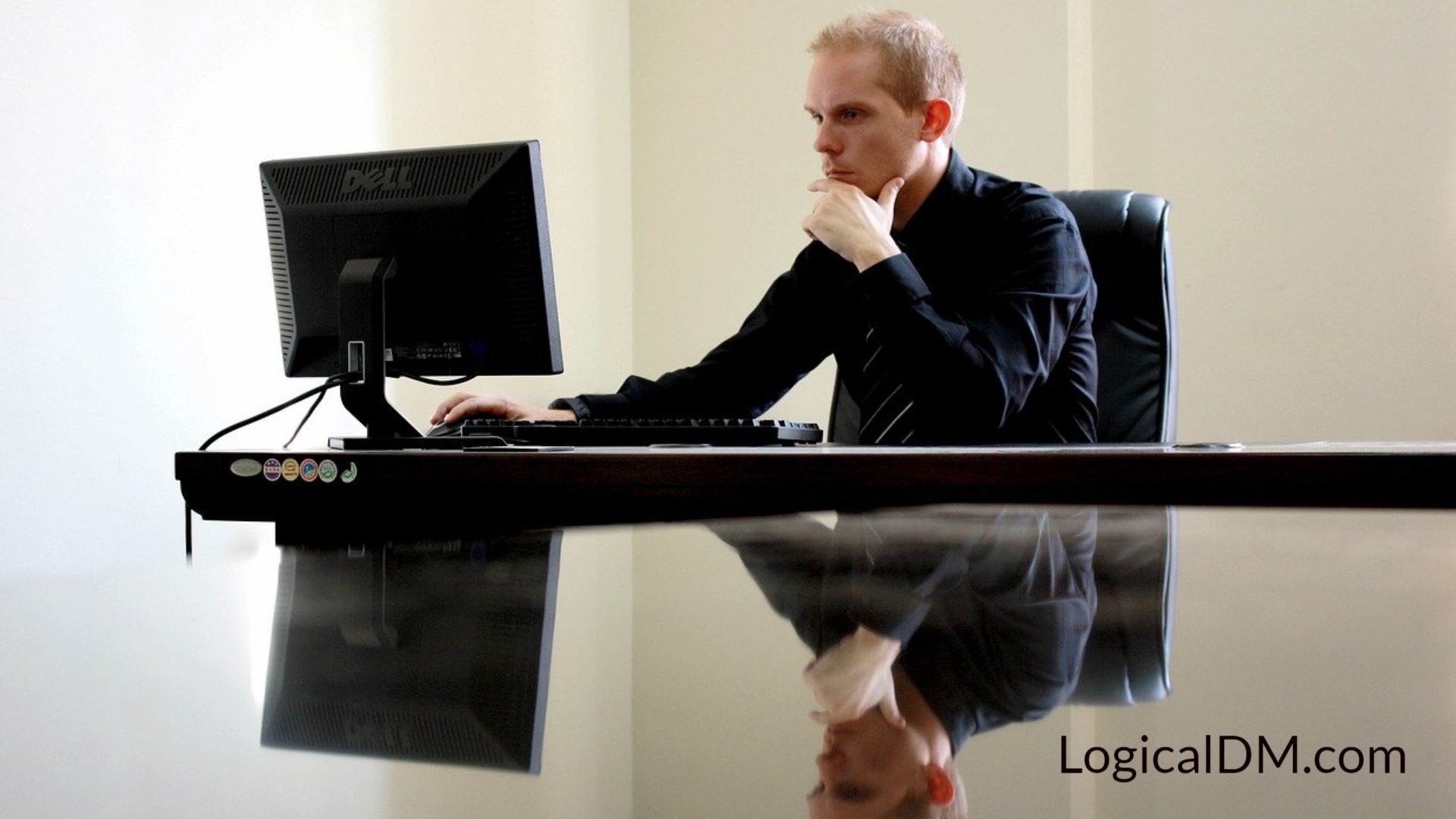 male sitting at desk looking at computer monitor