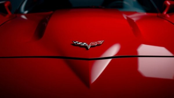 Close-up of Corvette emblem on red hood, emphasizing sleek design.