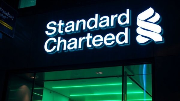 Standard Chartered logo glowing on building at night in Singapore, related to stablecoin credit card.