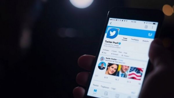 Smartphone screen with verified Twitter profile, xAI profitability timeline concept, in dark lighting.