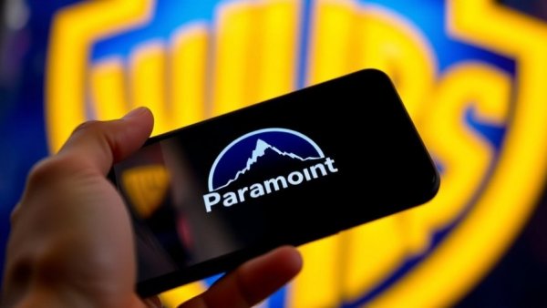 Paramount logo on phone with Warner Bros logo background. Warner Bros Paramount takeover bid.