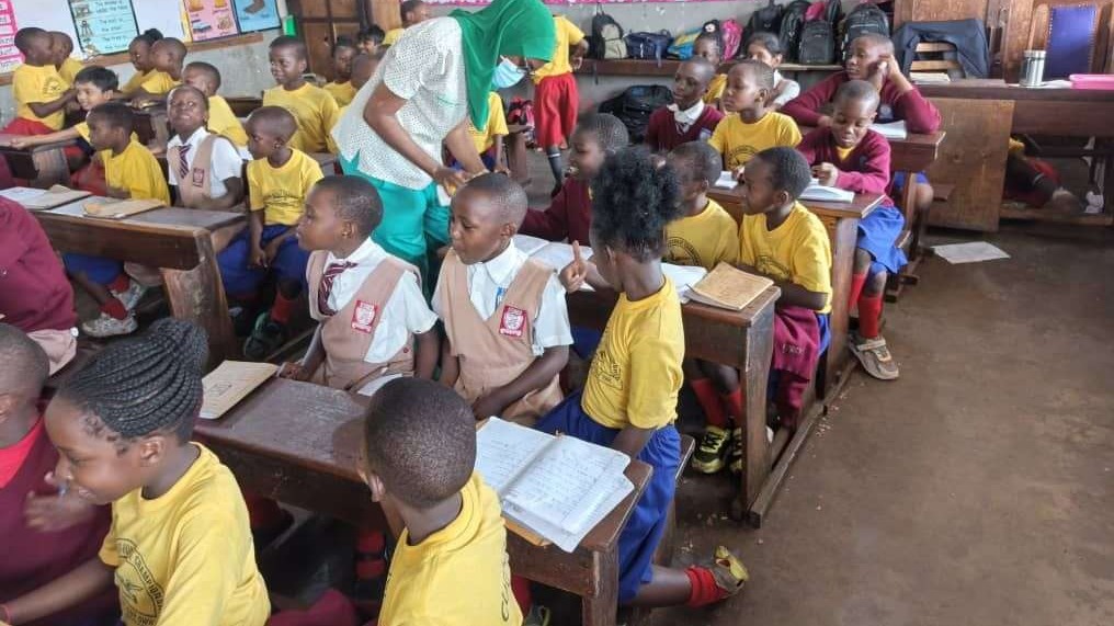 Teacher administers medicine to children in classroom during World Immunization Week.