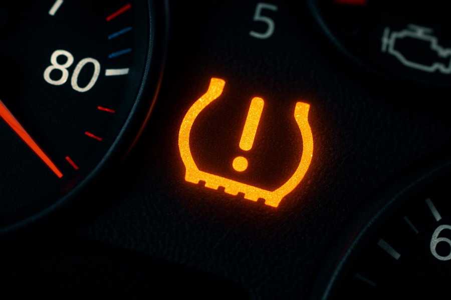 Close-up of a car dashboard with glowing tire warning light for tire pressure maintenance.