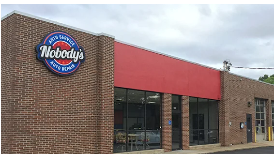 Auto repair shop exterior showcasing steering and suspension services in daylight.