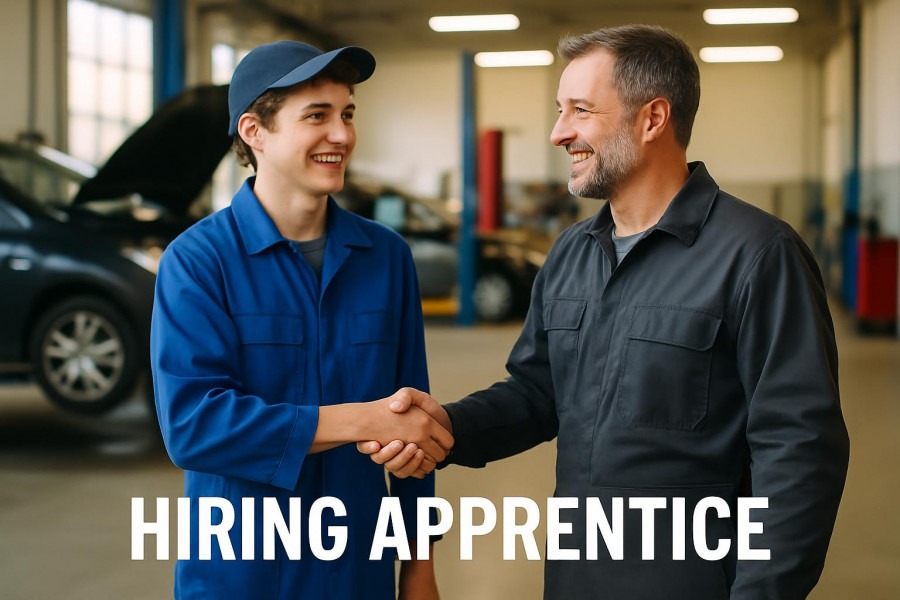Smiling apprentice and technician shaking hands in a bright auto repair garage, showcasing auto repair training.