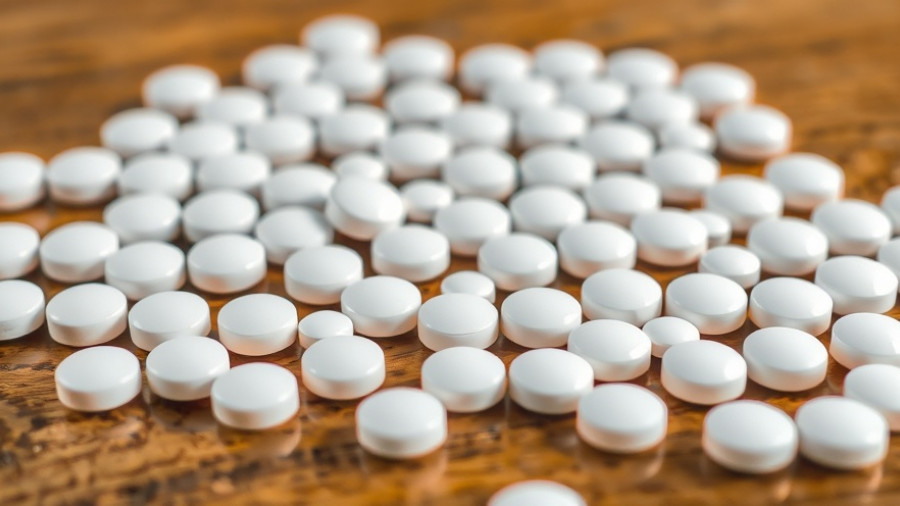 Various white tablets scattered on a wooden table.