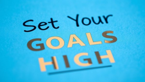 Motivational 'Set Your Goals High' text on blue paper for Michigan entrepreneur success stories.