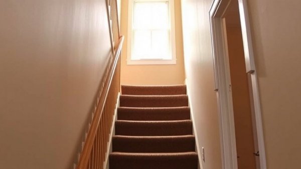 Plain staircase before makeover with brown carpet and beige walls.