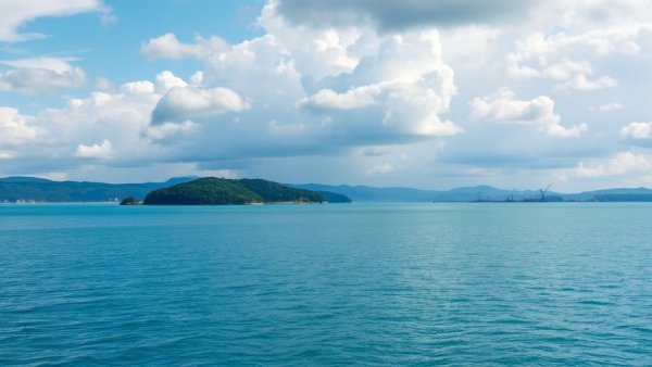 Scenic lake with distant island and industrial cranes under cloudy sky on pilgrimage to Varadahalli.