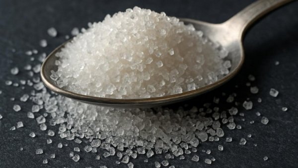 Granular sugar crystals heaped on a spoon highlighting Tagatose health benefits.