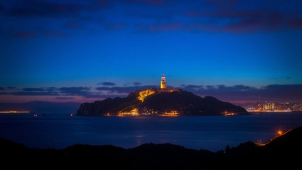 Alcatraz Night Tour: Alcatraz Island glowing at night with lighthouse.