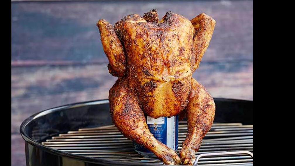 Smoked Beer Can Chicken on grill with smoky background.