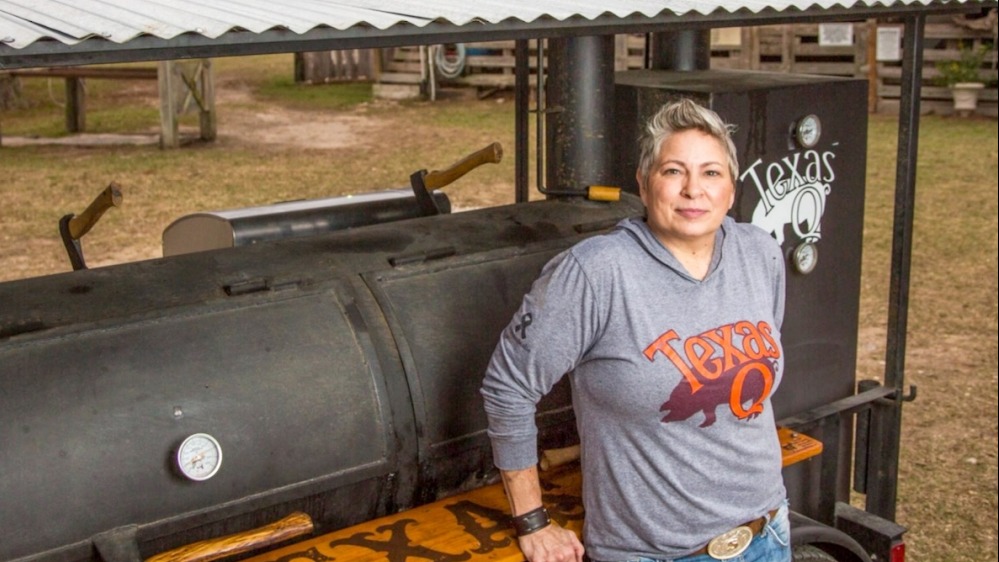 Pitmaster by BBQ smoker in rustic Texas setting