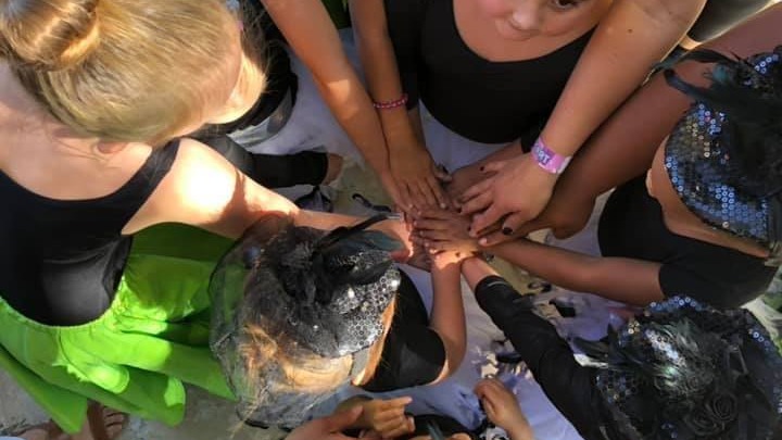 Happy diverse group of dancers holding hands in circle celebrating inclusive dance programs at MCDC
