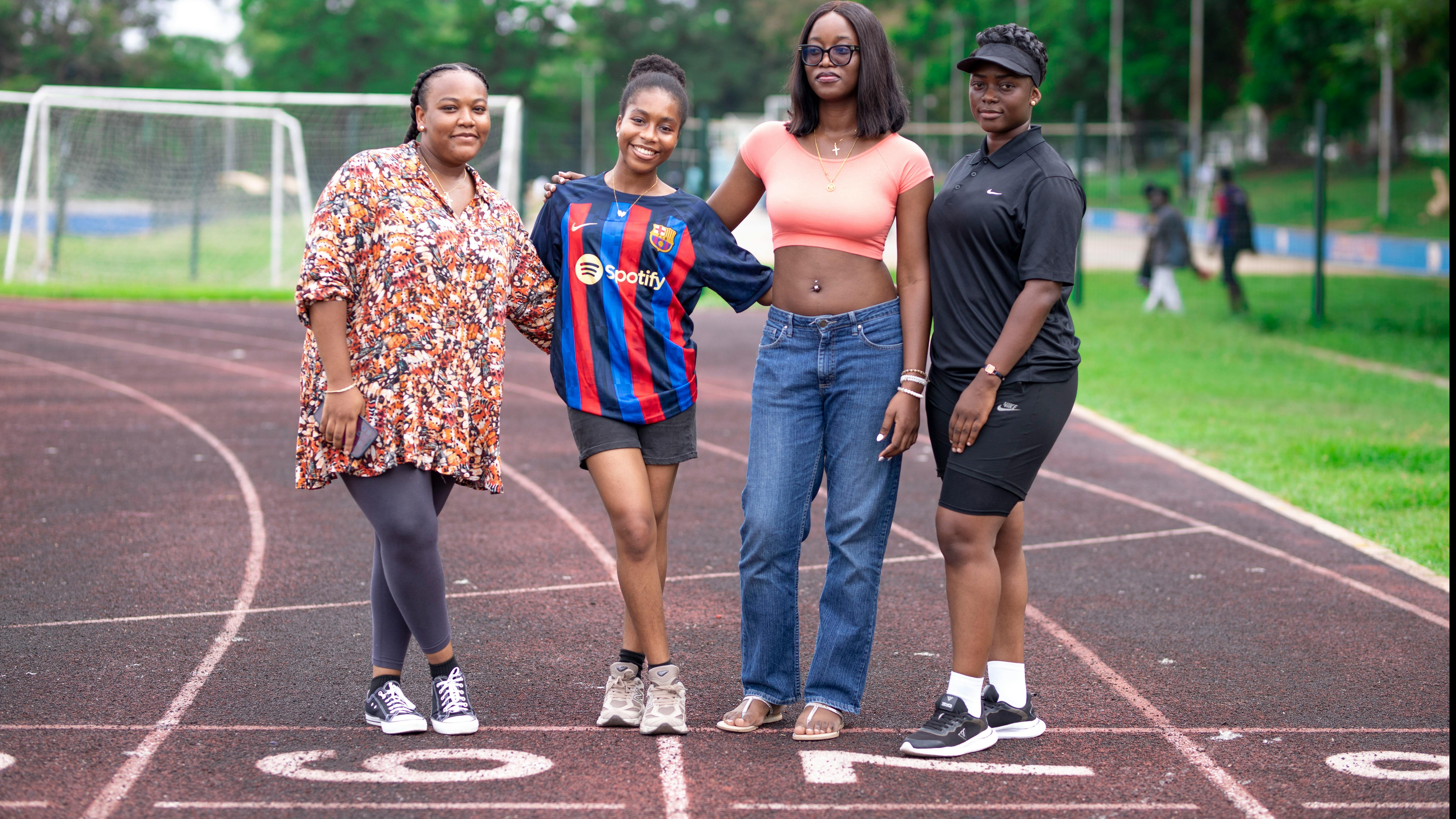 Athletes perform team rituals with stretches on grass field.