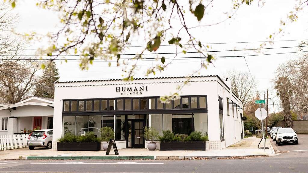 Welcoming Pilates studio with warm lighting, friendly interactions, and a calm atmosphere.