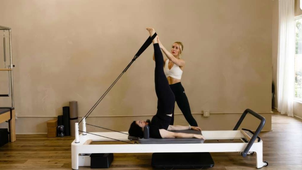 Group Pilates class with individualized guidance on reformers.