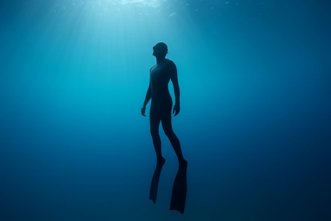 Free diver underwater symbolizing breath mastery and mental calm.