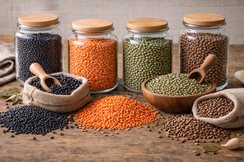 Colorful variety of lentil beans on display in glass canisters, bowl, and burlap sacks