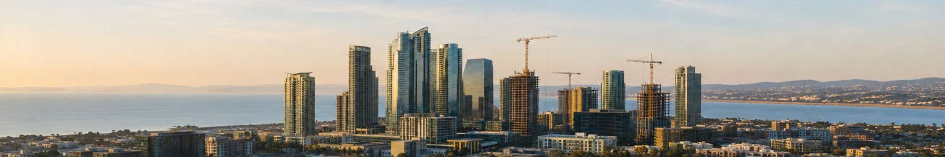 Modern coastal city skyline with active tower cranes and high-rise construction
