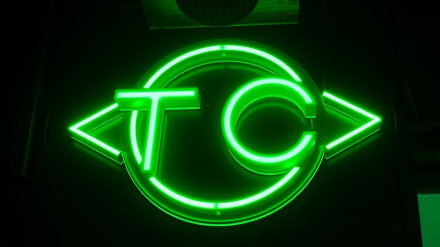 Glowing neon TC sign in dark room related to political deepfake controversy.
