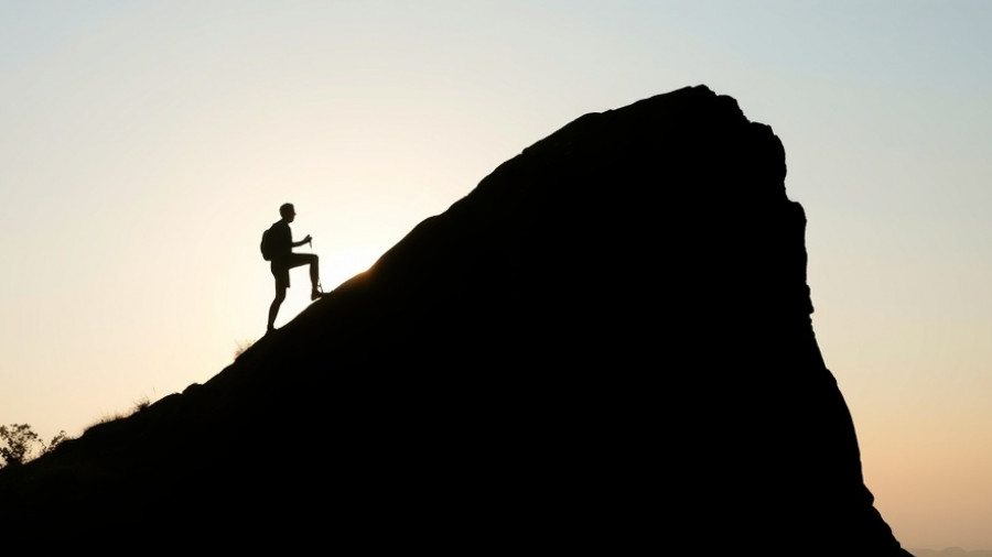 Silhouette of a person climbing a hill at sunrise, symbolizing letting go of mindfulness results.