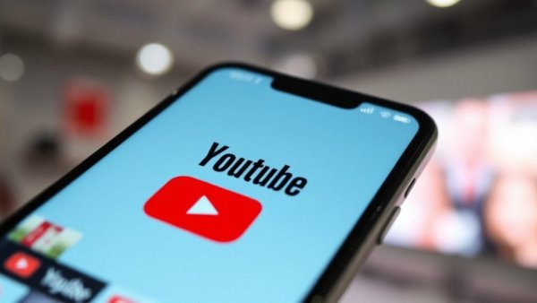 Close-up of YouTube logo with video thumbnails blurred.