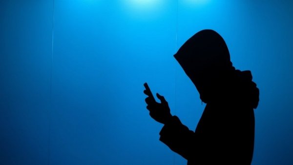 Silhouetted person with phone behind blue frosted glass, mysterious ambiance