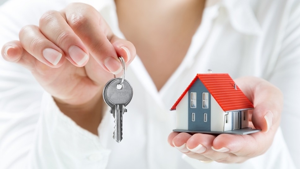 Person holding up keys to a small house