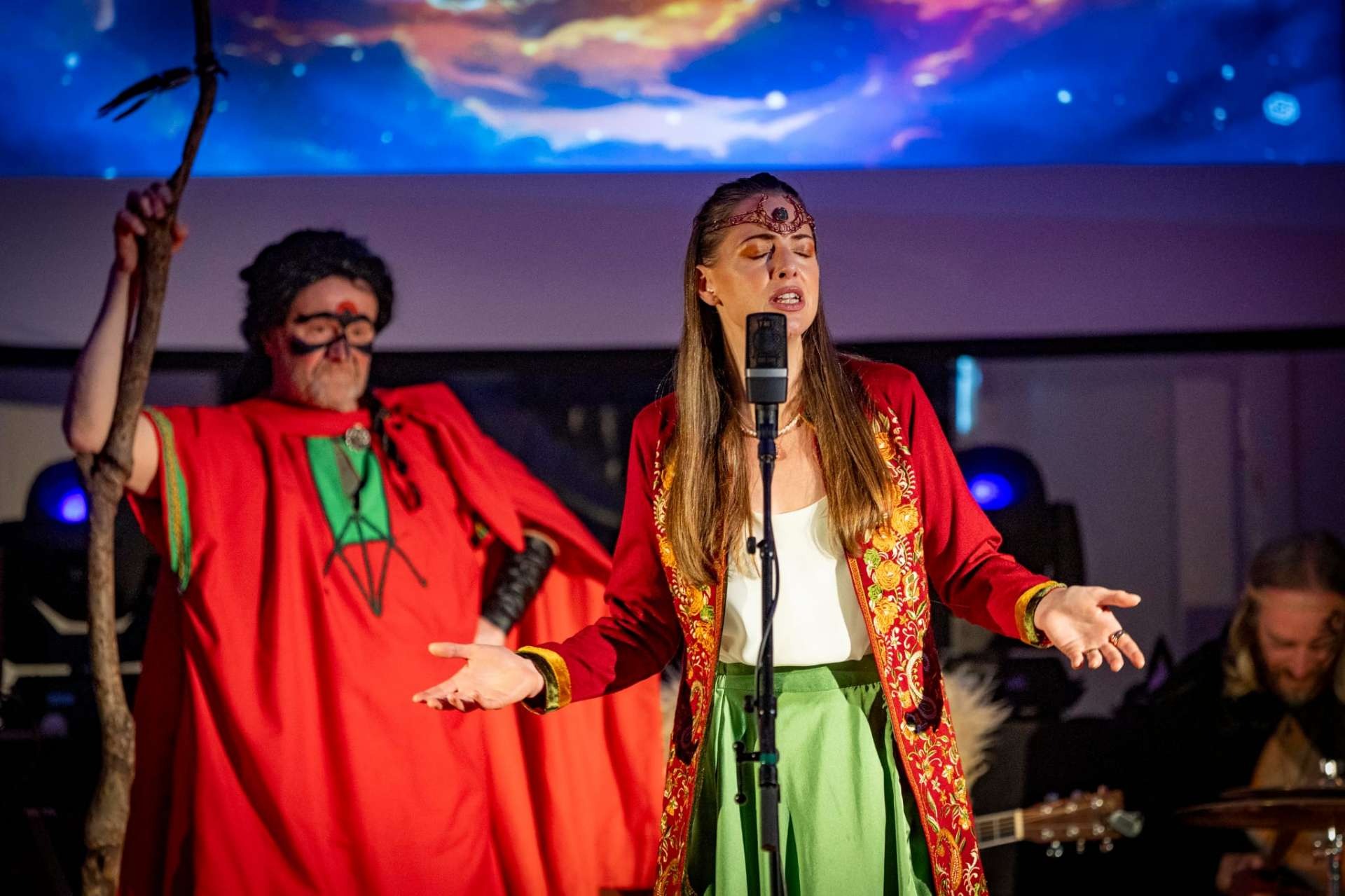 Foinse performers on stage in red costumes during Cú Roí MacDara