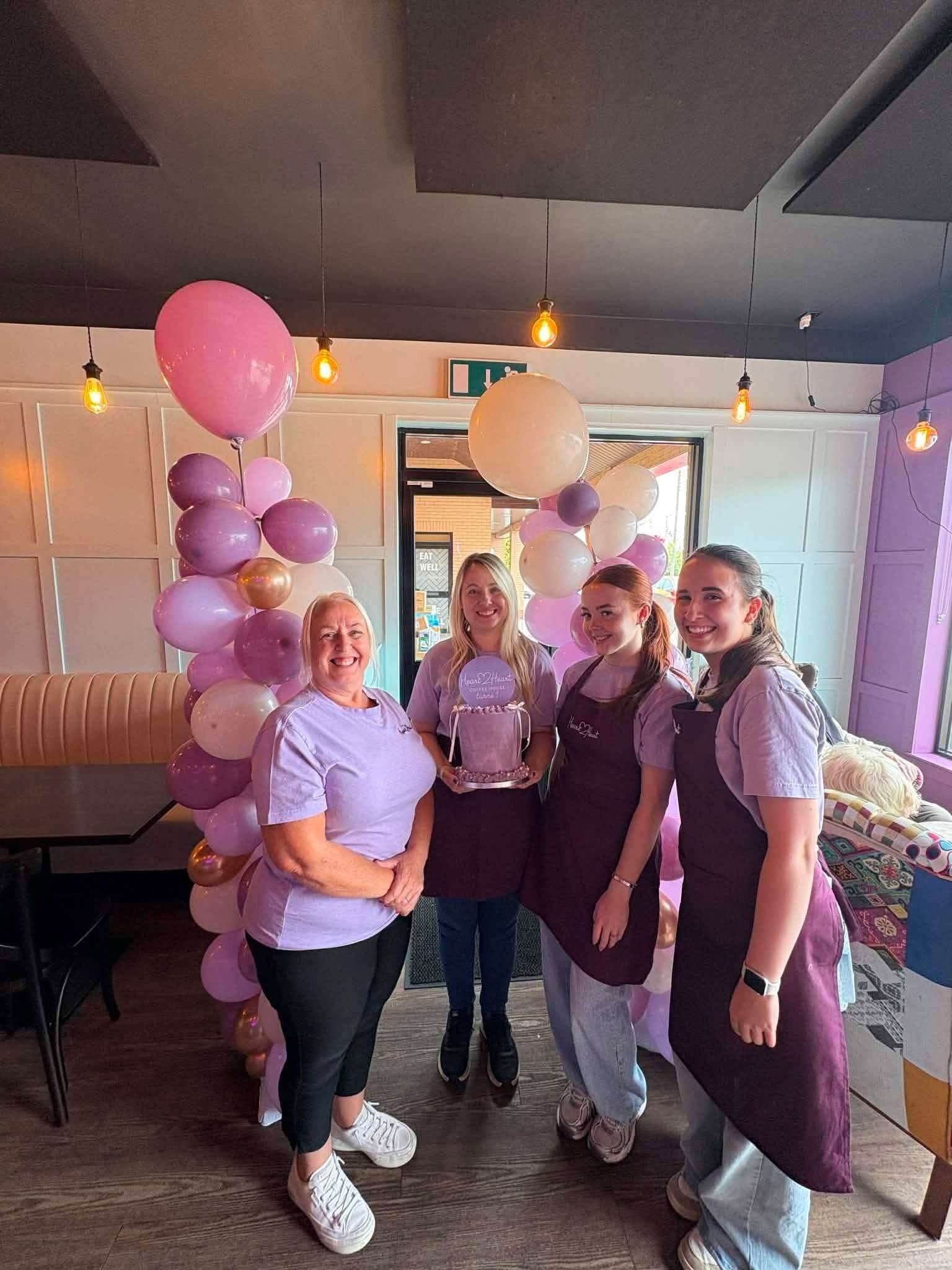 The Heart 2 Heart Coffee House team celebrating the first anniversary with balloons.